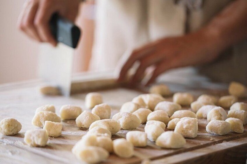 A person rolling out dough on a wooden surface. 5