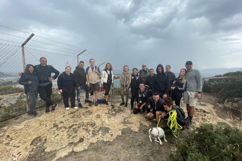 A group of people on a rocky terrain with a chain-link fence in the background. 3