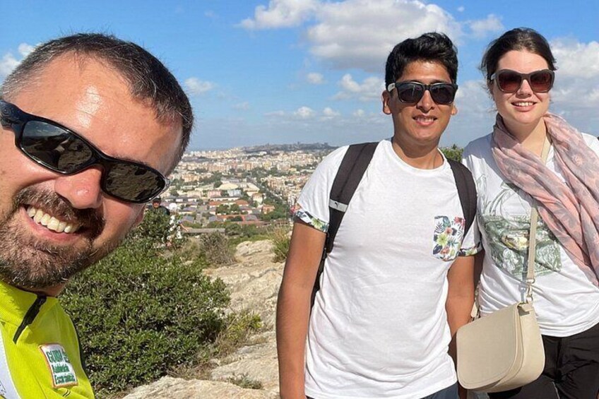 Three people standing on a hill overlooking a cityscape. 1