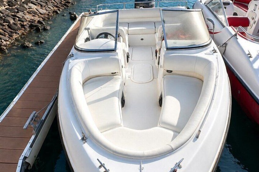A white motorboat docked at a pier with a wooden walkway. 4