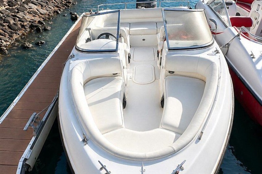Een witte motorboot ligt aan een houten steiger, met een rotsachtige kustlijn op de achtergrond. 4