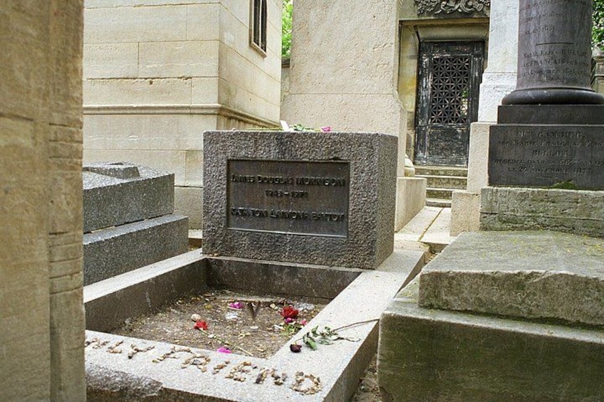 A gravestone with inscriptions, a stone bench, and a building entrance. 3
