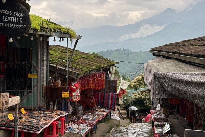 A market with stalls selling leather goods, surrounded by mountains. 4
