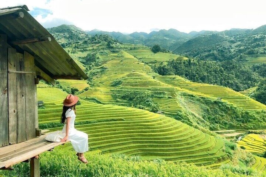 A woman sitting on a bench overlooking terraced fields. 1