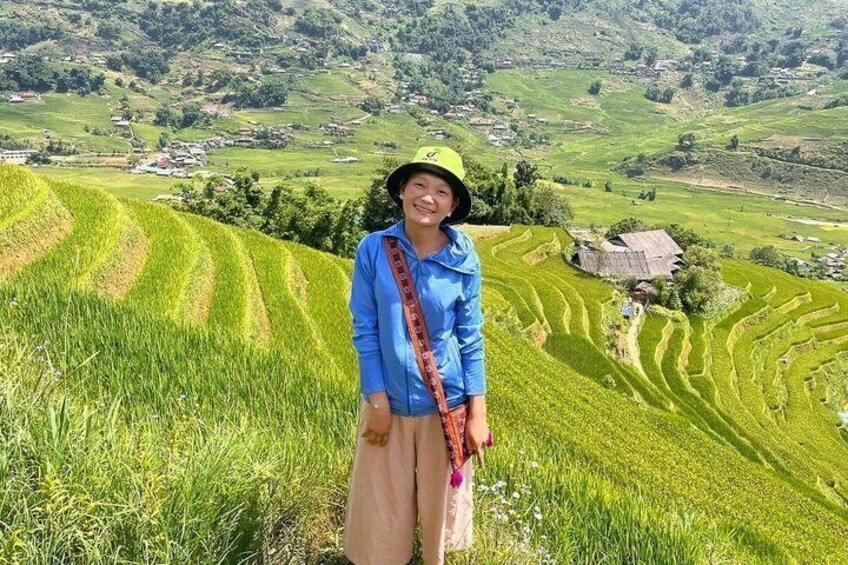 A person standing in a terraced rice field with a mountainous landscape in the background. 4