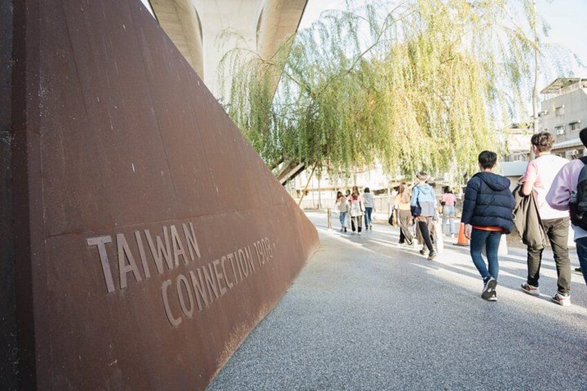 A pedestrian walkway with a large brown structure labeled 'Taiwan Connection 1998'. 2