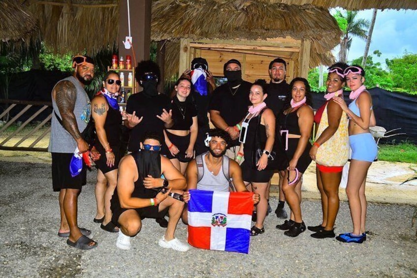 A group of people posing for a photo in front of a thatched-roof structure. 5