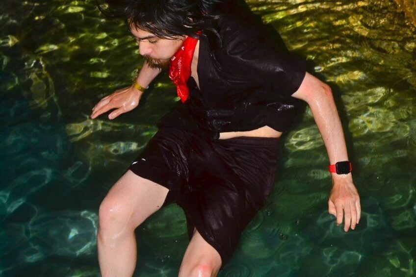 A person in black swimwear and a red bandana, partially submerged in clear water. 2