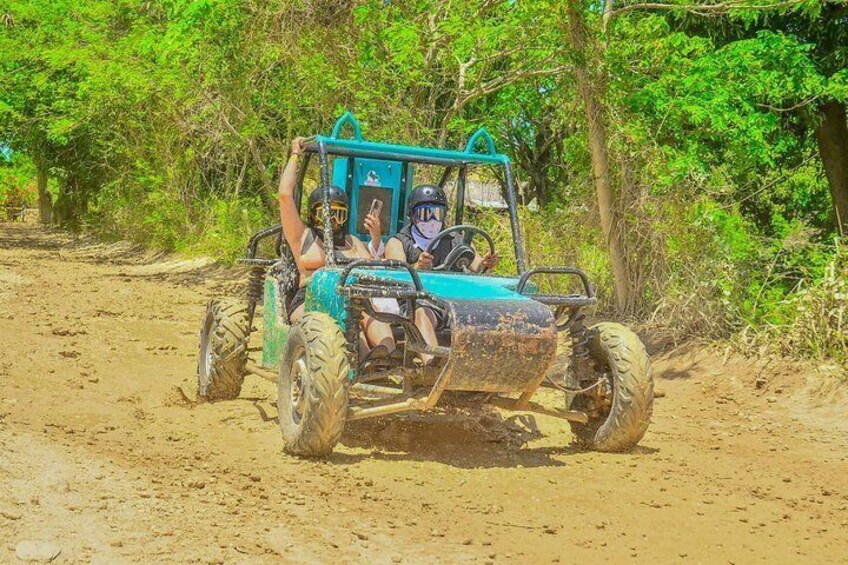 A blue off-road vehicle on a dirt path surrounded by greenery. 3