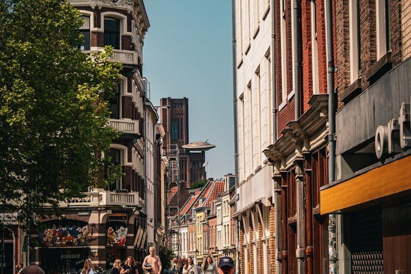 A bustling urban street lined with historic buildings, a tree, and pedestrians. 2