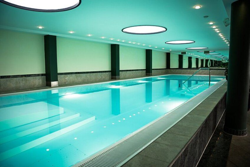 A long indoor swimming pool with a tiled floor and a series of lights on the ceiling. 2
