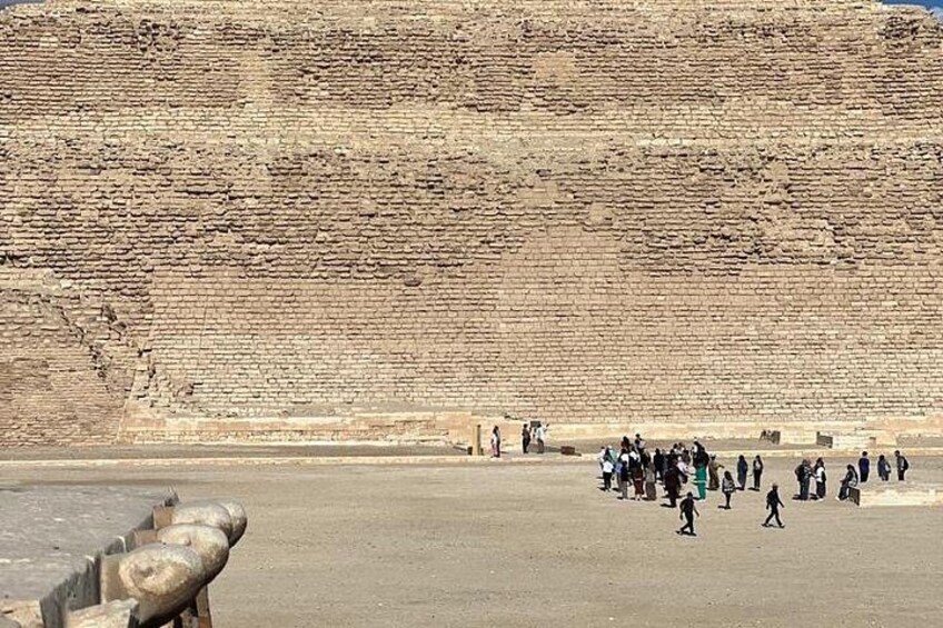 A large brick wall with people walking in front of it. 1