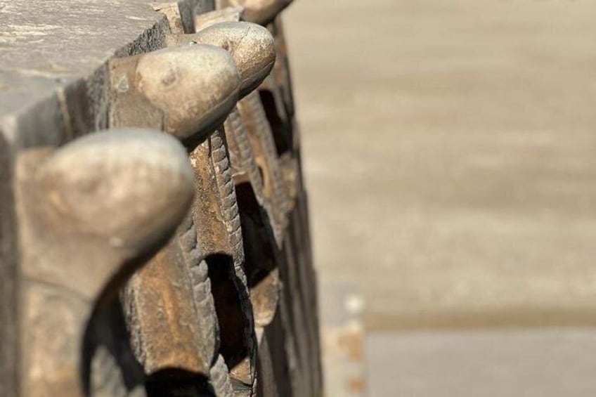 A close-up of a vehicle's wheel well with visible lug nuts and a rusted metal surface. 1
