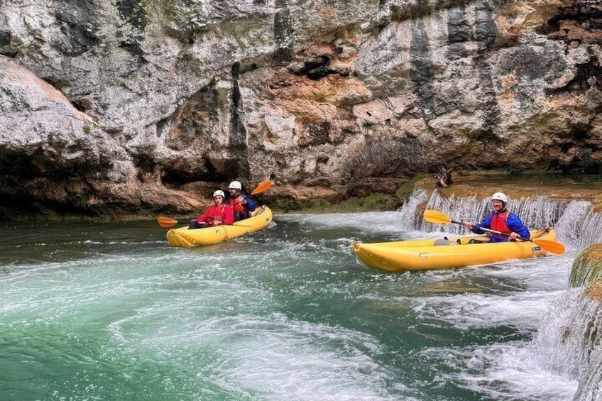 Two people kayaking on a river with a waterfall in the background. 4