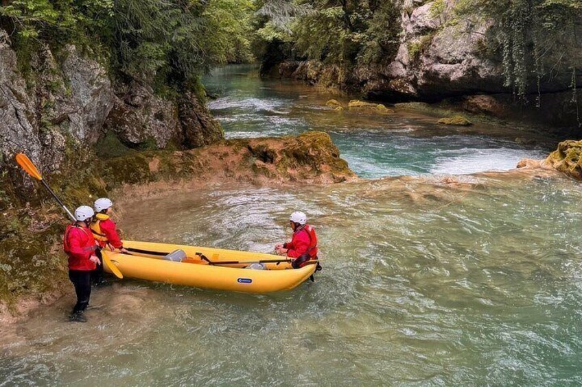 A group of people in a yellow raft on a river surrounded by rocky terrain. 2