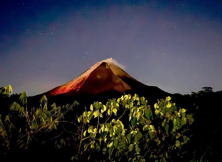 A volcano at night with a glowing lava flow at its peak and stars in the sky. 2