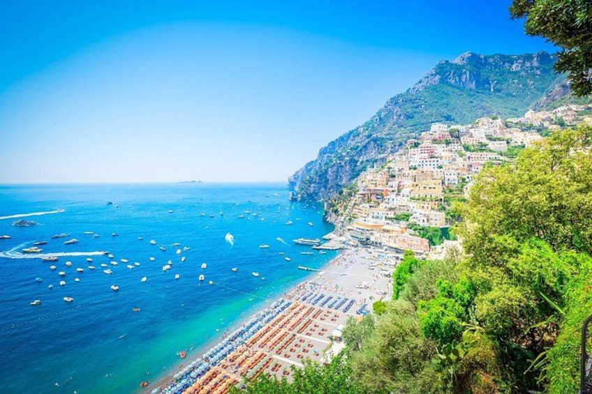 A coastal town with a beach, boats, and buildings on a hillside. 2