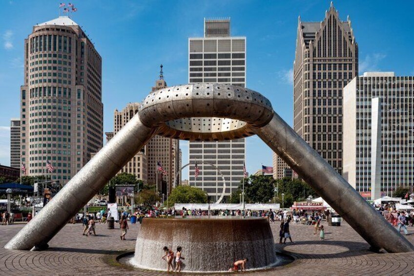 A large metallic sculpture in a public square with tall buildings in the background. 5