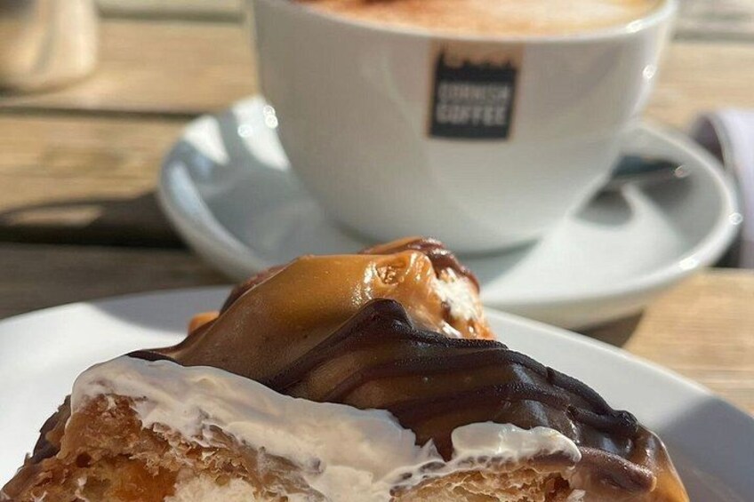 A pastry with chocolate and cream on a plate, a cup of coffee with a label, and a wooden table. 5