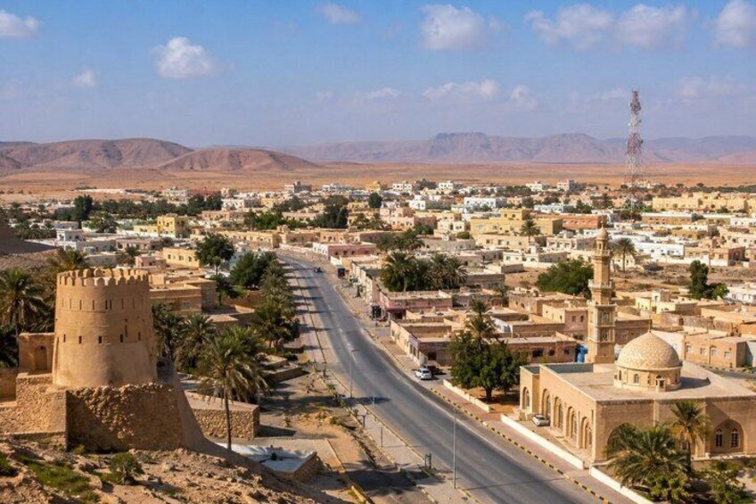 A desert town with a prominent tower, a mosque with a dome, and a clear road leading through the settlement. 1