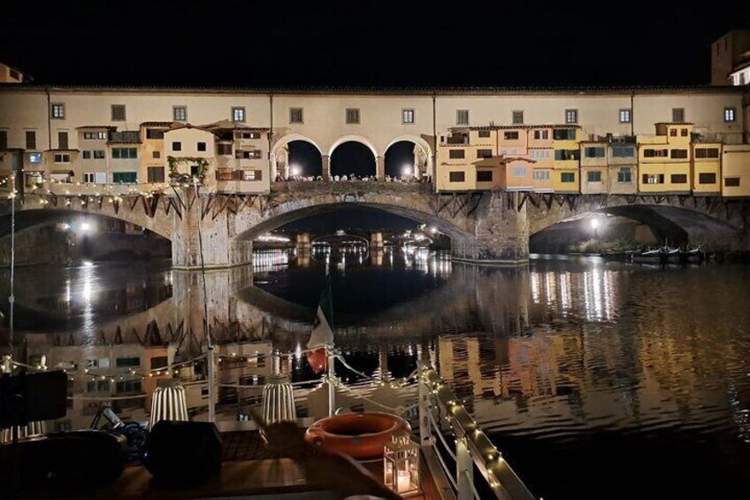 A nighttime riverside scene with a bridge, illuminated buildings, and a boat dock. 5