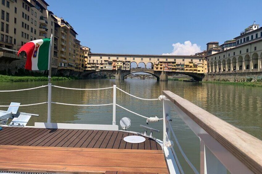 A wooden deck with a flag, a river, and a bridge in the background. 1