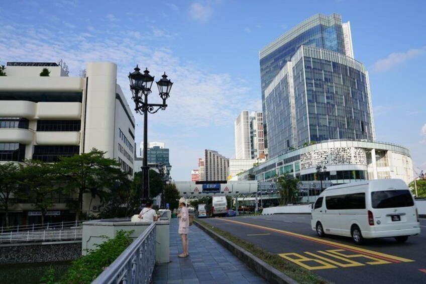 A city street with a white van, a pedestrian, and modern buildings. 1