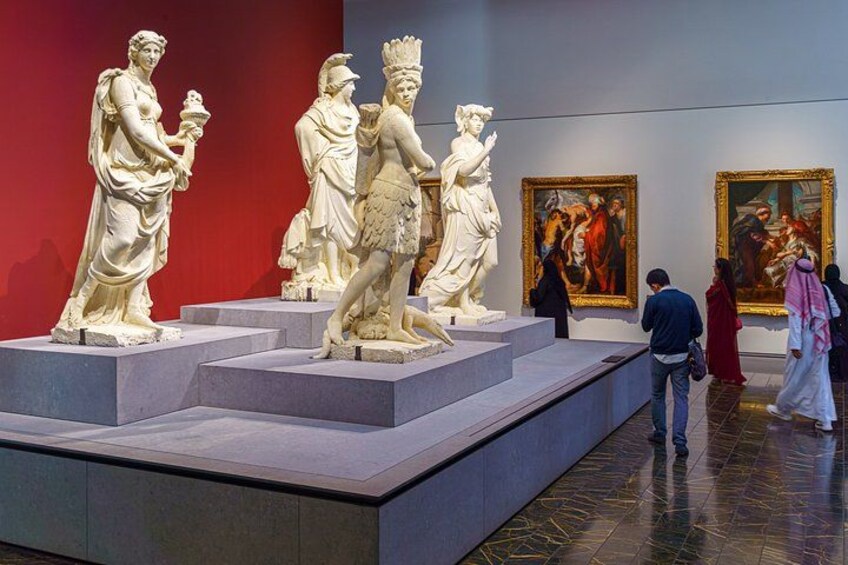 Marble statues, classical paintings, and a red wall in a museum. 3