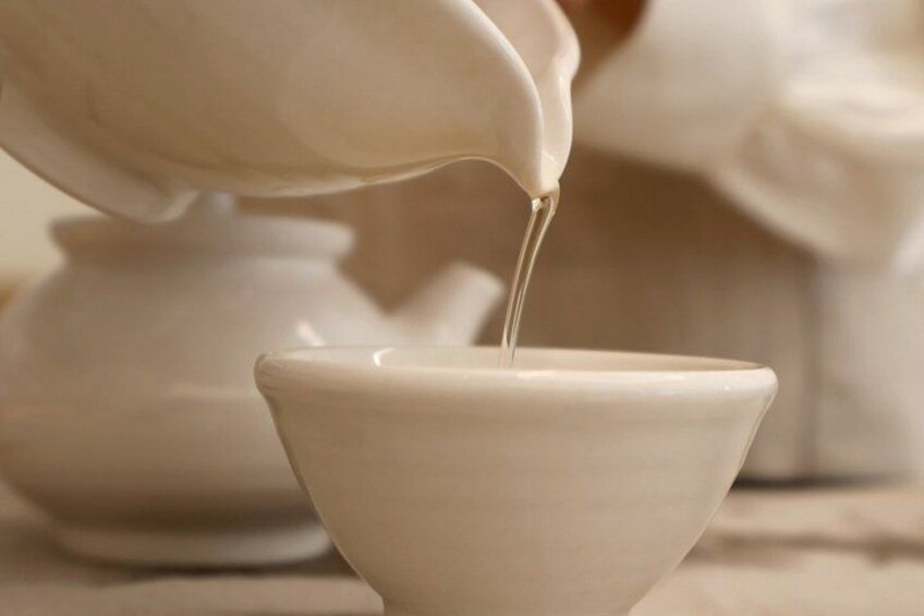 A ceramic bowl being filled with a liquid from a jug. 4