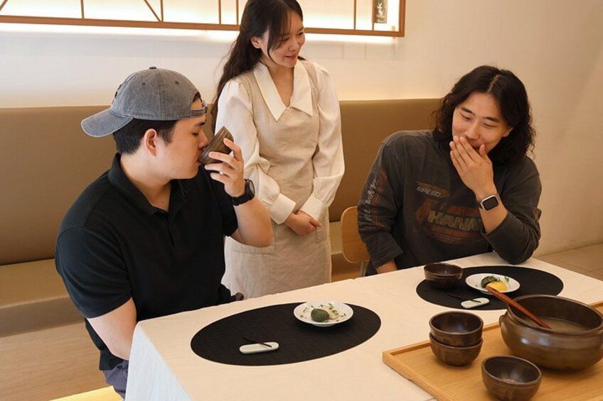 A dining table with bowls and chopsticks, a person wearing a cap, and another person in a white blouse. 3