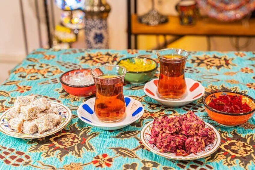 A table with various dishes and glasses of tea, set on a patterned tablecloth. 2