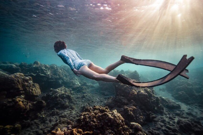 A person scuba diving underwater with fins and sunlight filtering through the water. 5