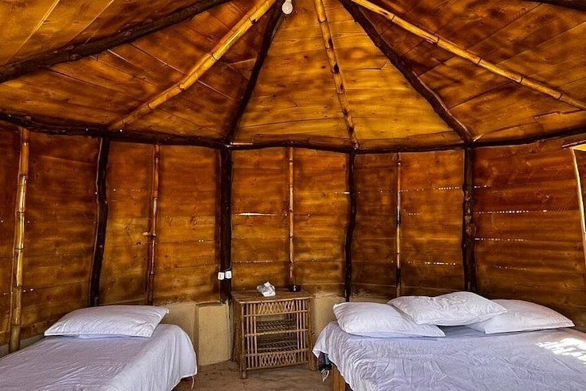 A wooden cabin with two beds, a small table, and a slanted roof. 2