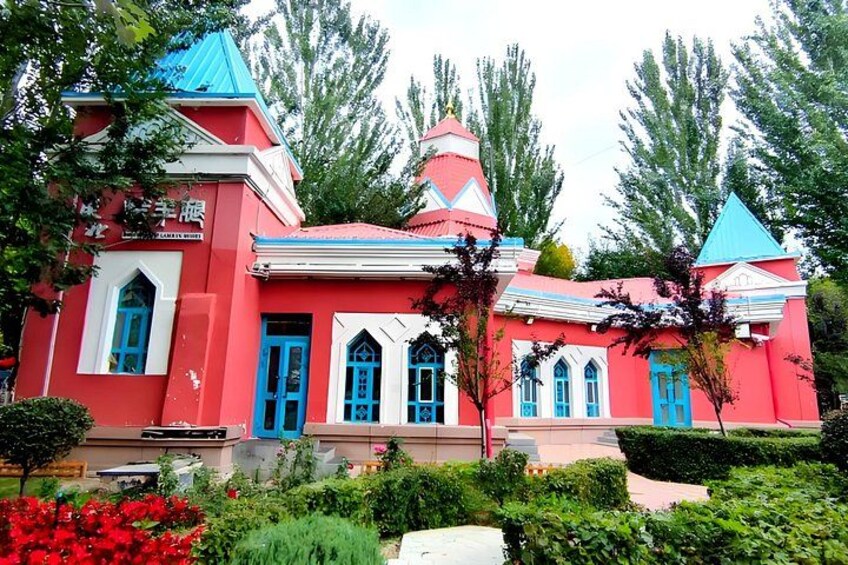 A colorful building with red and blue accents, surrounded by lush greenery and trees. 4