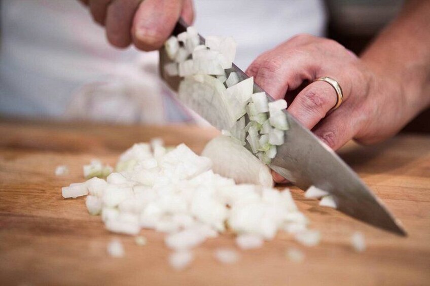 A person chopping onions on a wooden cutting board. 4