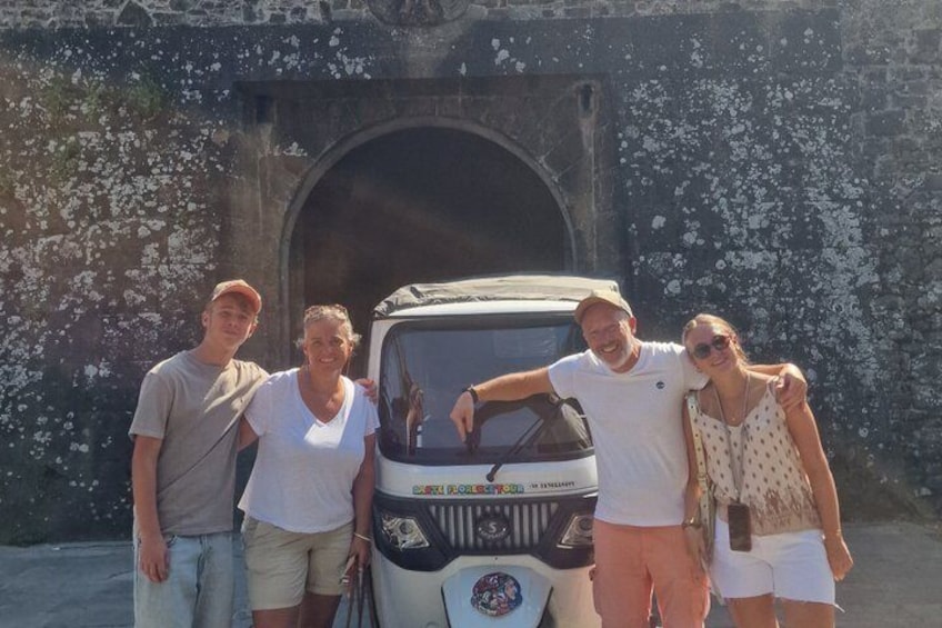 A group of people posing in front of a vehicle with a tunnel in the background. 4