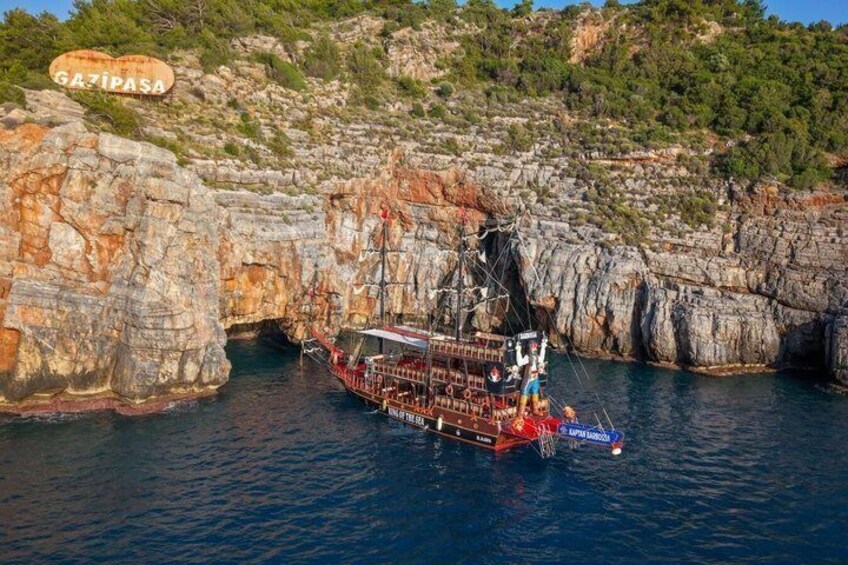 A ship anchored near a rocky coastline with a sign reading 'GAZIPASA.' 3