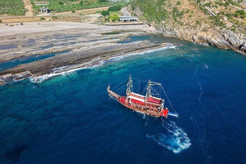 A large fishing boat in the ocean near a rocky coastline. 5