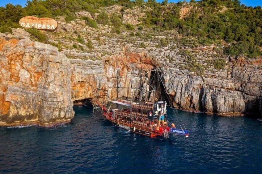 A ship navigating through a rocky coastal area with a sign reading 'GAZIPASA' in the background. 2