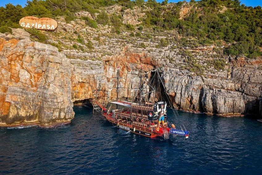 A ship navigating through a rocky coastal area with a sign reading 'GAZIPASA' in the background. 2