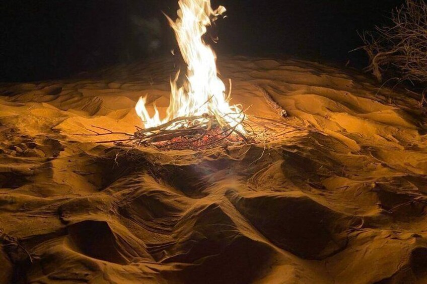 A campfire in a sandy area at night. 5