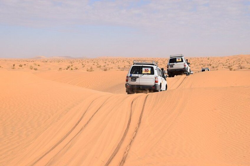 Two off-road vehicles on a sandy desert terrain. 1