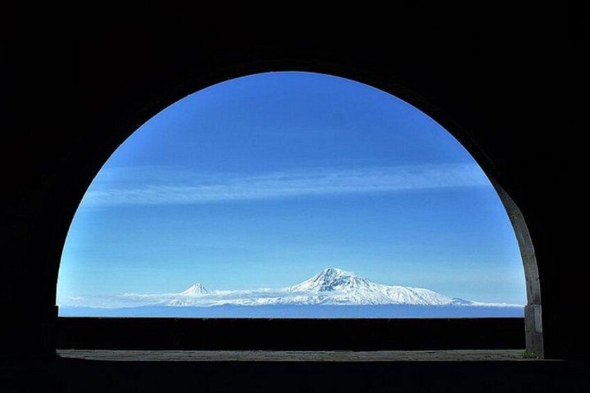 A snow-capped mountain through a semi-circular window. 2