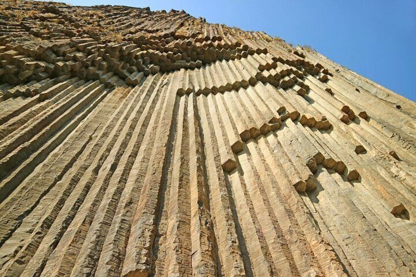 A large rock formation with horizontal striations and a series of rectangular indentations. 4