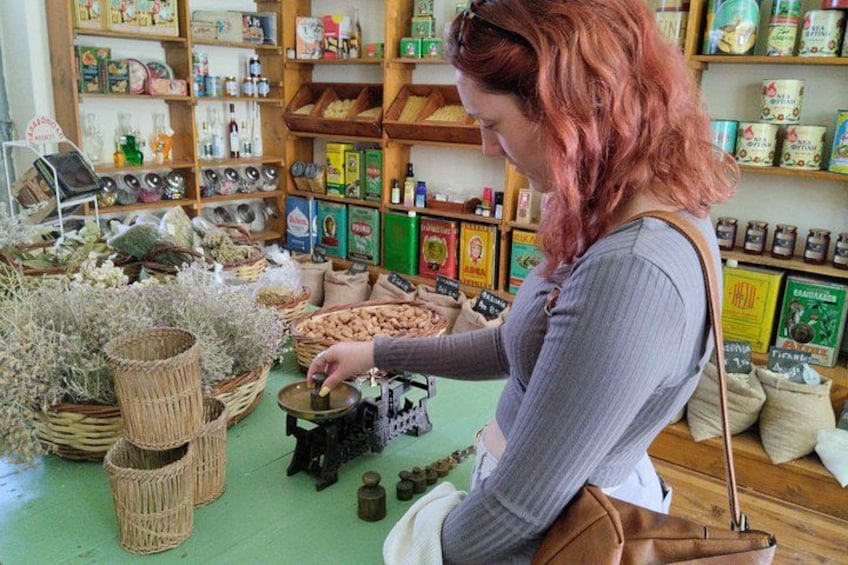 A woman examining items on a table in a store with shelves of products in the background. 5