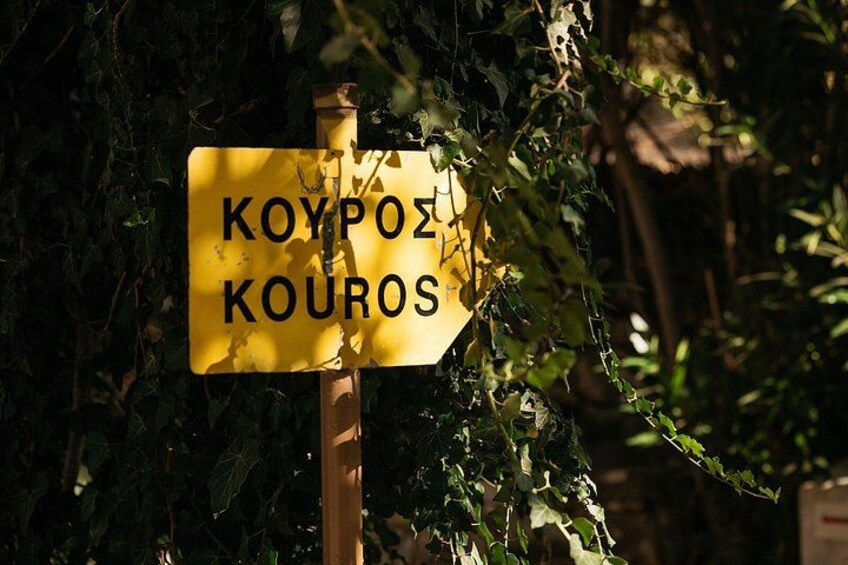 A yellow sign with black lettering, partially obscured by foliage. 5