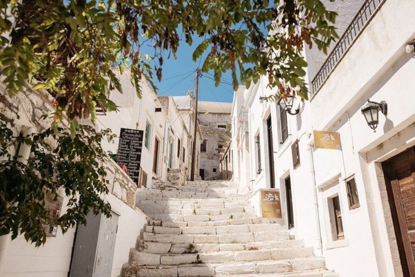 A narrow street with stone steps leading up to a building, surrounded by white walls and wooden doors. 3