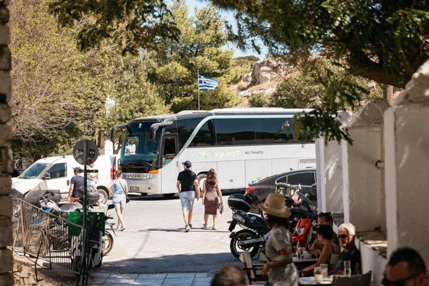 A bus, people walking, and parked motorcycles. 5