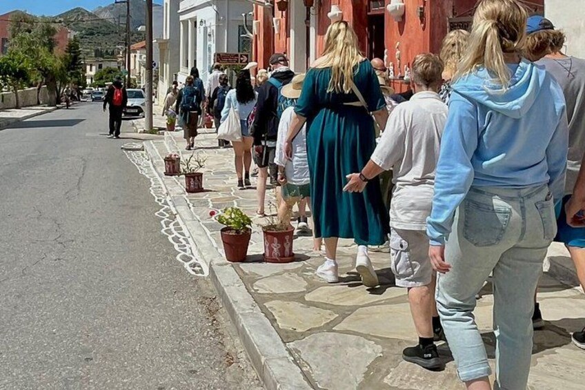 A group of people walking on a street lined with potted plants and buildings. 5