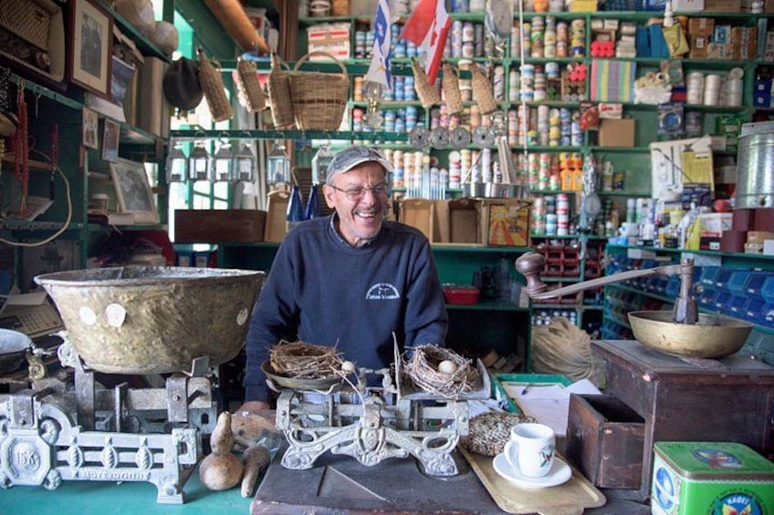 A shop with various items on shelves, a large metal pot, and a person standing in front. 4